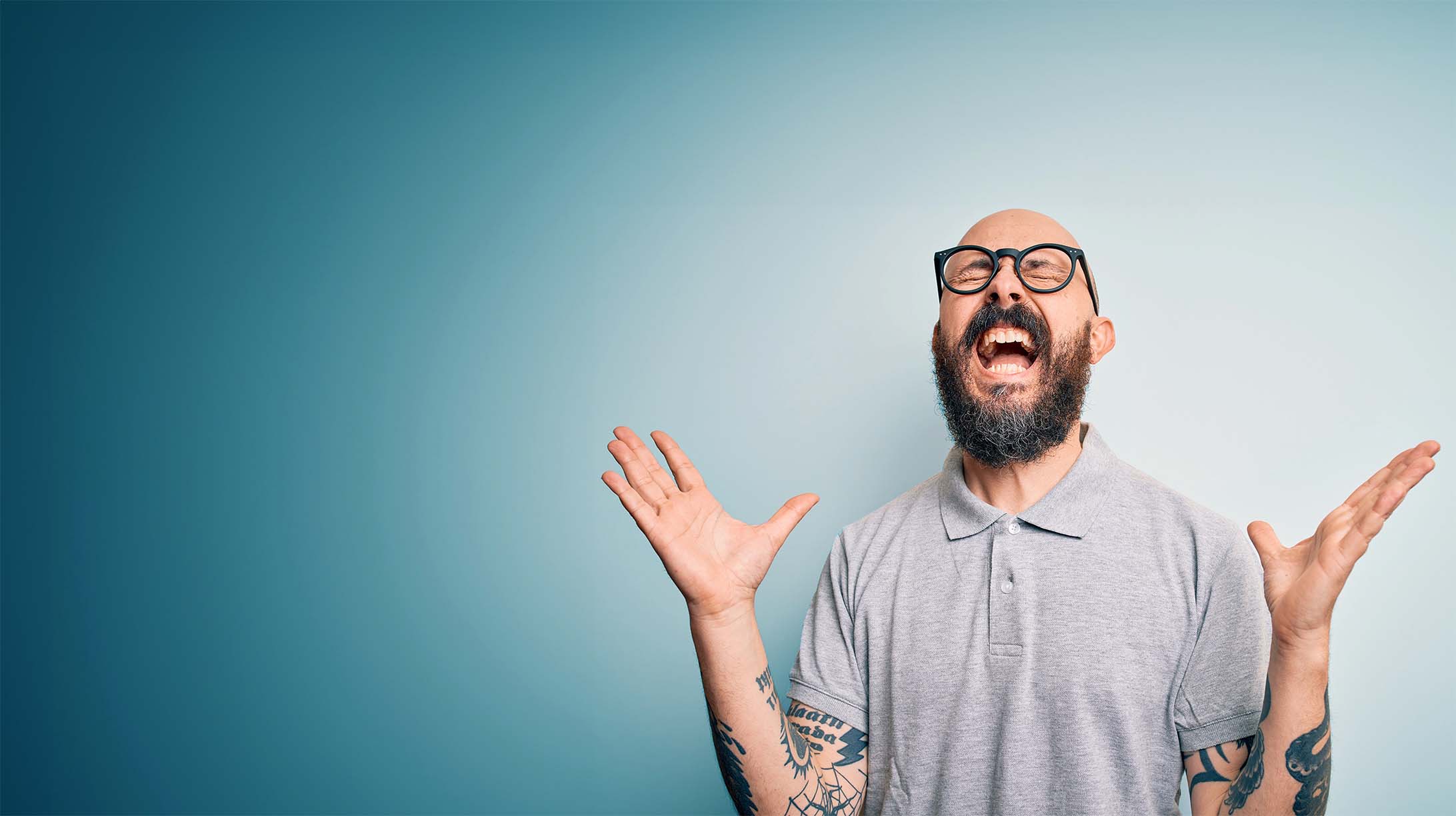 Man with a beard and glasses making an expressive gesture against a blue background