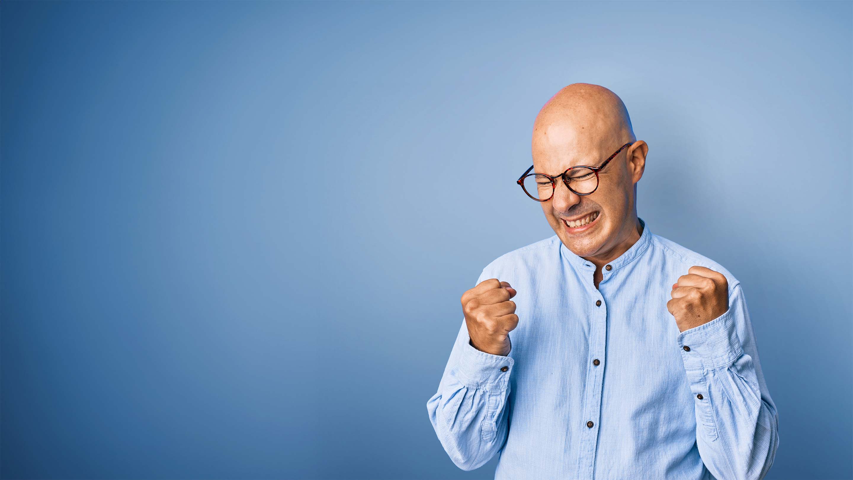 Bald man with glasses celebrating with closed fists