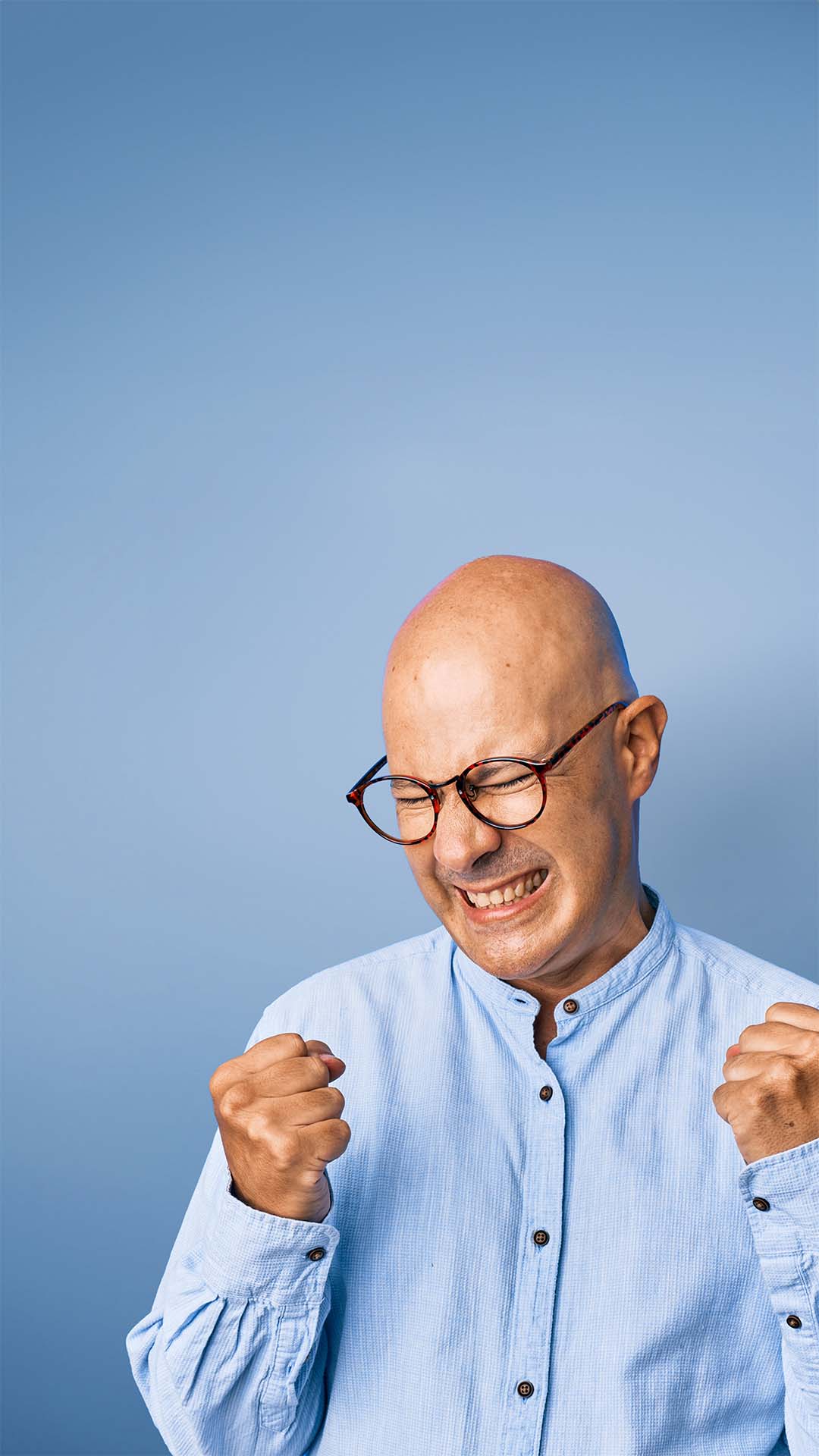 Bald man with glasses celebrating with closed fists