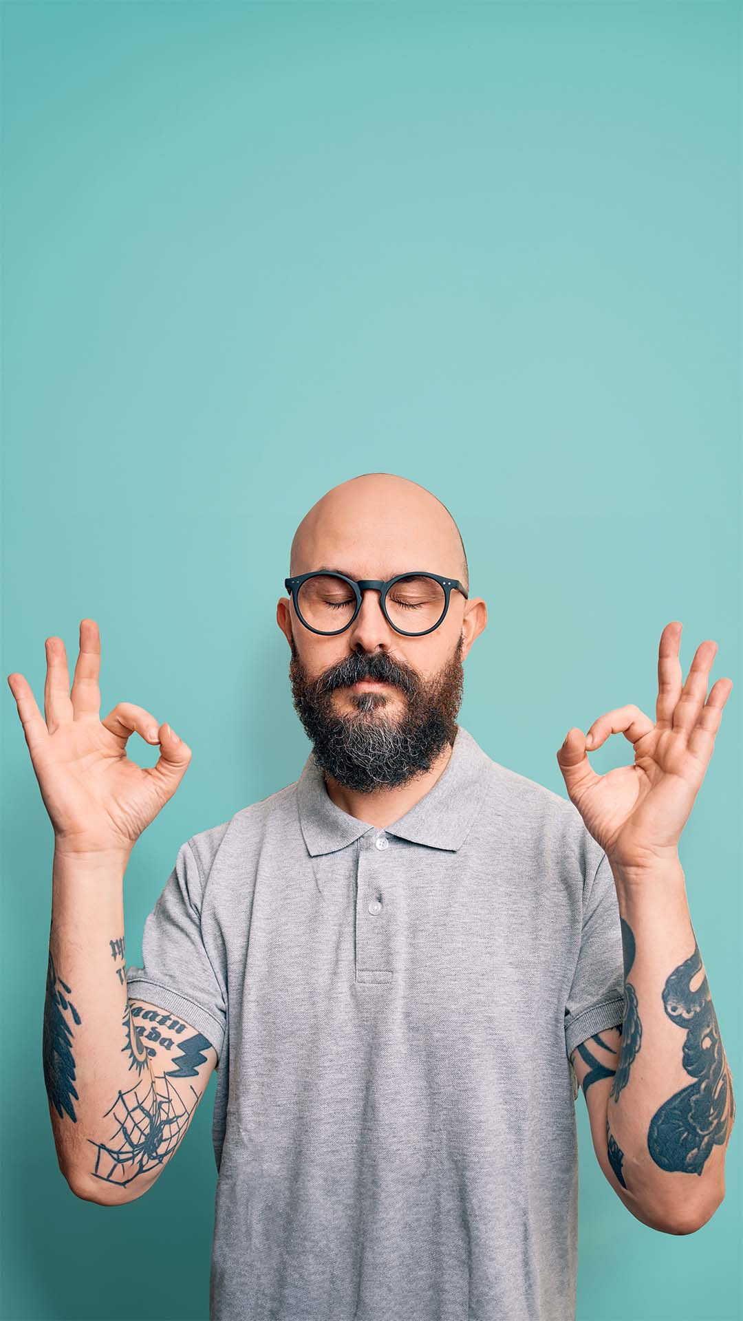 A bald man with glasses does okay peace sign with both hands
